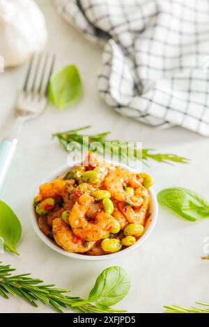 Frischer Salat mit Garnelen und Edamame Sojabohnen in einer Schüssel auf einem weißen Tisch. Stockfoto