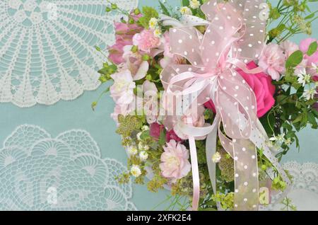 Romantische Hochzeitsdekoration: Blumenstrauß aus rosa und weißen Blumen auf minzfarbiger Tischdecke mit regionalem Häkelmuster. Geringe Schärfentiefe. Stockfoto