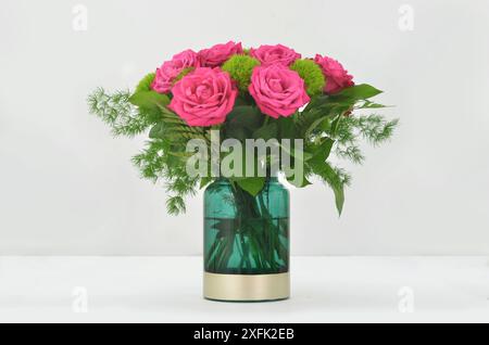 Eleganter Blumenstrauß aus rosa Rosen in grüner Vase auf hellem Hintergrund. Stockfoto