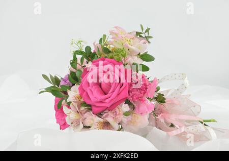Romantischer Hochzeitsstrauß aus weißen und rosafarbenen Blumen, der weißen Tüll liegt. Stockfoto