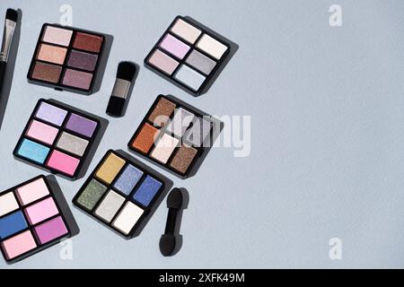 Ein Satz mehrfarbiger Lidschatten und Pinsel auf blauem Hintergrund. Augen-Make-up. Stockfoto