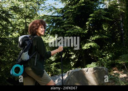 Eine junge Frau lächelt, als sie an einem sonnigen Sommertag durch einen üppigen Wald wandert. Stockfoto