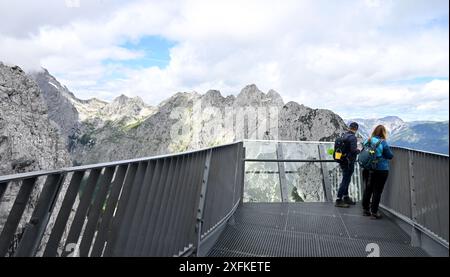 Garmisch Partenkirchen, Deutschland. Juli 2024. Wanderer stehen auf der Aussichtsplattform (2050 Meter) der Alpspitze am Osterfelderkopf und blicken hinunter ins Höllental, rund 1000 Meter darunter. Quelle: Peter Kneffel/dpa/Alamy Live News Stockfoto