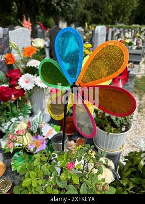 Buntes Windrad auf dem Grabstein auf dem öffentlichen Friedhof Stockfoto