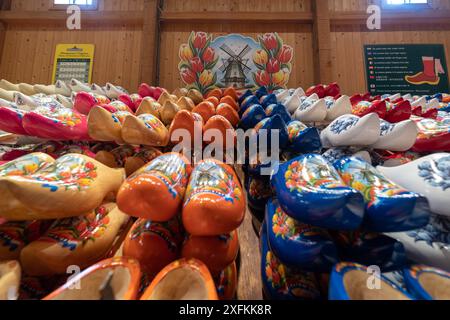 Eine Reihe farbenfroher Clogs wird in einem Geschäft ausgestellt. Die Clogs haben verschiedene Farben und Designs, darunter Orange, Blau und weiß. Das Display ist arran Stockfoto