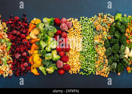 Zubereitung von frischem Gemüse im Sommer für den Winter, verschiedene gefrorene Gemüse und Beeren auf dunkelblauem Hintergrund, Draufsicht Stockfoto