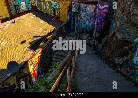 Auf dem Hügel Cerro Alegre in Valparaíso, Chile, befindet sich eine dunkle Treppe, umgeben von Graffiti-Kunstwerken. Stockfoto