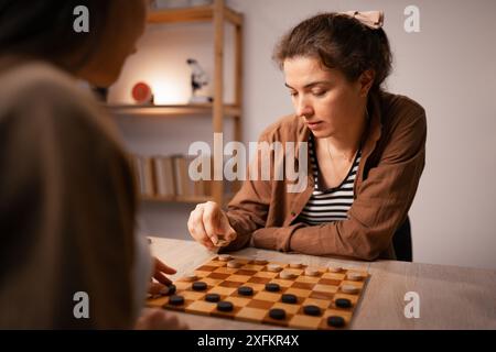 Zwei Frauen, die zu Hause Checkers spielen, engagieren sich für Freizeitaktivitäten im Brettspiel Stockfoto