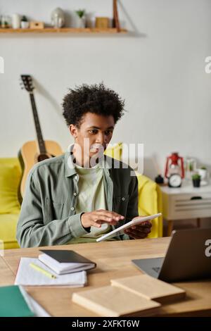 Junger afroamerikanischer Mann, der sich auf den Laptop-Bildschirm konzentriert, während er zu Hause studiert. Stockfoto
