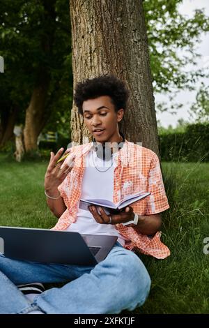 Junger Mann, Laptop, Kopfhörer, Natur umarmen. Stockfoto