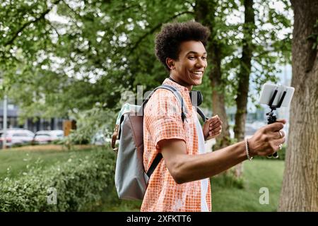 Ein junger Mann mit Rucksack macht ein Handyfoto. Stockfoto