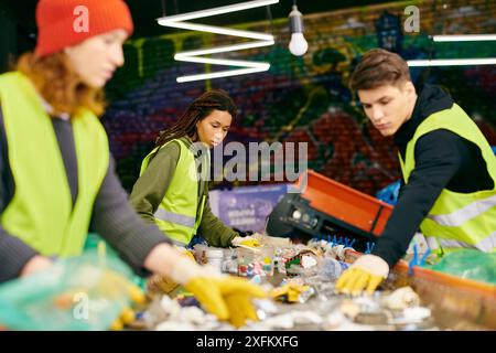 Junge Freiwillige in Sicherheitswesten und Handschuhen arbeiten zusammen, um Müll auf dem Tisch zu sortieren. Stockfoto