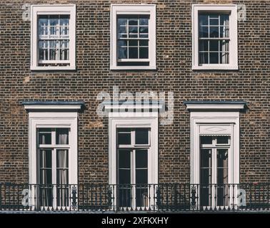 Drei weiße Fenster mit schwarzem Geländer am Brick Building in London. Stockfoto