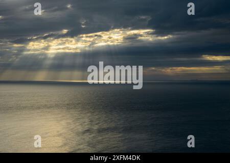 Sonnenstrahlen brechen durch dunkle Wolken über dem Meer des Ärmelkanals in Kent, Großbritannien. Juli Stockfoto