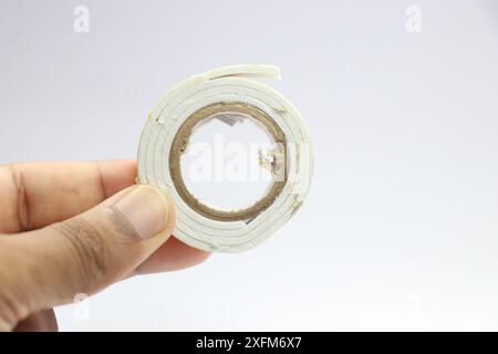 Doppelseitiges Klebeband zum Verbinden von zwei in der Hand gehaltenen Gegenständen mit der Seitenansicht Stockfoto