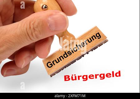 Grundsicherung ein Holzstempel ist beschriftet mit dem Aufdruck: Grundsicherung und dem Abdruck: Bürgergeld *** Grundeinkommensförderung Eine Holzmarke ist beschriftet Stockfoto