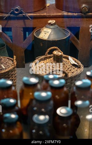 Eine Sammlung alter Flaschen und Gläser, von denen einige mit dem Wort „Wein“ gekennzeichnet sind. Die Flaschen sind in einem Display angeordnet, einige davon sind t Stockfoto