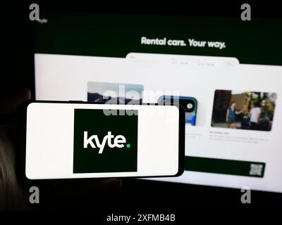 Person mit Smartphone und Logo der US-amerikanischen Autovermietung Kyte Systems Inc. Vor der Website. Schwerpunkt auf dem Display des Telefons. Stockfoto