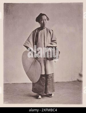 Vintage-Foto der chinesischen Dame in traditioneller Kleidung. Illustrations of Qing China, 1875 dieses Dienstmädchen ist ein Sklavenmädchen, das in der Kindheit für einen geringen Betrag von ihren armen Eltern gekauft wurde, da weibliche Kinder in vielen Teilen Chinas, wo noch immer Kindermord praktiziert wird, zu einem traurigen Rabatt kommen. Dieses Mädchen wurde im Busen der Familie aufgezogen und trainiert, auf die Damen des Haushalts zu warten, sich um die Kinder zu kümmern und sich allgemein nützlich zu machen. Auf diesem Bild ist sie auf dem Weg zum Markt dargestellt, die Sklavin genießt mehr Freiheit im Ausland als ihre Geliebte. In ihrer Linken Stockfoto