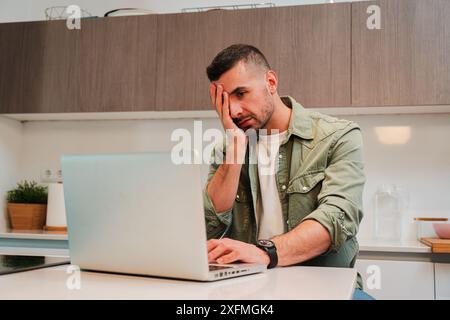 Ein hart arbeitender Mann, verzweifelt wegen Laptop-Problemen, die ihr Stress und Kopfschmerzen verursachen. Ein frustrierter Burnout-Typ, der mit übermäßiger Arbeit zu tun hat Stockfoto