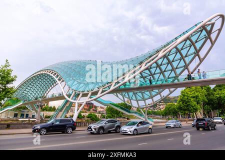 Tiflis, Georgien – 17. Juni 2024: Die Friedensbrücke ist eine bogenförmige Fußgängerbrücke, eine Stahl-Glas-Konstruktion über den Fluss Kura, die die Brücke verbindet Stockfoto