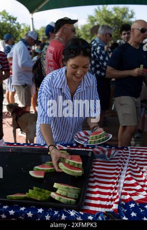 Austin, Texas, USA, 4. Juli 2024. Eine Frau nimmt Wassermelonenscheiben während der jährlichen Feier zum 4. Juli in Barton Hills auf. Einige hundert Einwohner gingen auf der 1/2 km langen Paraderoute zum Spielplatz der Grundschule, wo sie Kekse, Wassermelonen und Eis genossen. Quelle: Bob Daemmrich/Alamy Live News Stockfoto