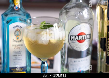 Bombay Sapphire Gin Flasche und Cocktailglas mit Gin Tonic und Martini Bianco Flasche, England. Konzept: Alkohol zu Hause Stockfoto