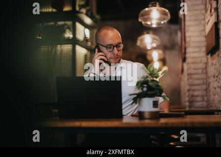 Geschäftsmann am Telefon und an Laptop in einem modernen Café Stockfoto