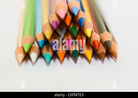 Ein Nahbild von mehrfarbigen Bleistiften, die in Pyramidenform auf weißem Hintergrund angeordnet sind und lebendige Farben und Kreativität zeigen. Stockfoto