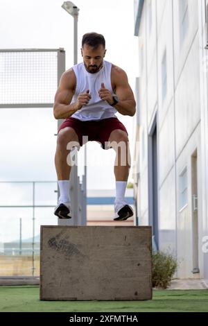 Ein Mann, der CrossFit macht und draußen auf eine Kiste springt. Stockfoto