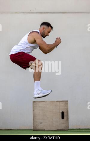 Ein Mann, der CrossFit macht und draußen auf eine Kiste springt. Stockfoto