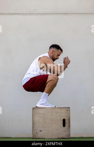 Ein Mann, der CrossFit macht und draußen auf eine Kiste springt. Stockfoto