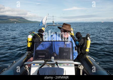 Drei Personen im Tauchboot, mit Tauchern, die sich bereit machen, ins Wasser zu gehen, Lamlash Bay, Isle of Arran, South Arran Marine Protected Area, Schottland, Großbritannien, August 2016. Stockfoto