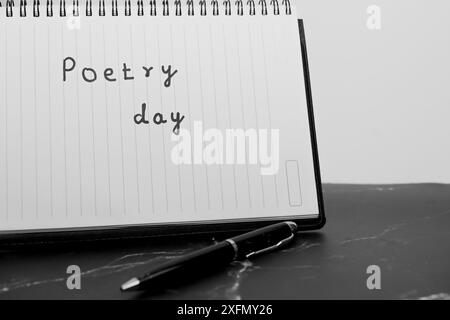 Ein Stift und ein Notizbuch mit dem Wort Poesie darauf. Der Stift ist schwarz und das Notizbuch ist spiralgebunden Stockfoto