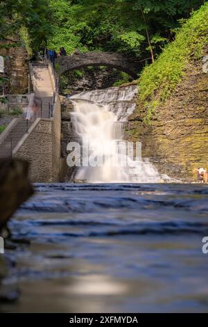 Vertikales Foto eines Wasserfalls mit einem Pfad / Betontreppe, Cascadilla Gorge Trail, in Ithaca, NY, USA. Stockfoto