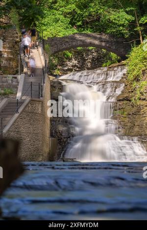 Vertikales Foto eines Wasserfalls mit einem Pfad / Betontreppe, Cascadilla Gorge Trail, in Ithaca, NY, USA. Stockfoto