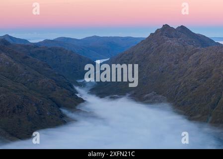 Berggipfel von Sgurr na h-Aide und Carn Mor über Temperaturumkehr in Glen Dessary, Knoydart bei Sonnenaufgang. Aus Sgurr Cos na Breachd-laoidh, Lochaber, Schottland, Vereinigtes Königreich, Oktober 2016. Stockfoto