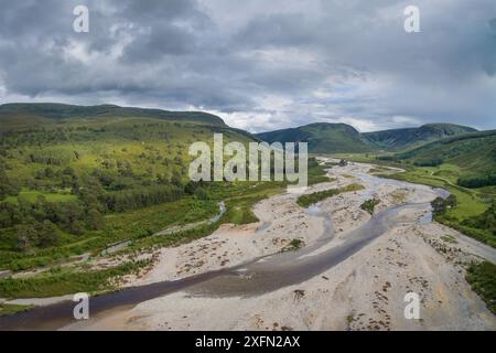 Luftaufnahme des geflochtenen Kanals des River Feshie, mit regenerierendem Kiefernwald (Pinus sylvestris) und Carn Dearg Mor im Hintergrund, Glenfeshie, Cairngorms National Park, Schottland, Vereinigtes Königreich, Juni 2016. Stockfoto