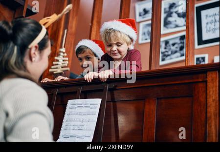 Mutter, Klavier und Kinder zu Weihnachten im Haus, Unterrichten und Binden mit Unterstützung, Liebe oder Fürsorge. Frau, Kinder und Tastatur zusammen zu Hause Stockfoto