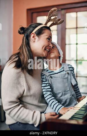 Mama, Junge und Klavier zu Weihnachten zu Hause zum Singen, Liebe oder Lernen für Musik, Aufführung oder Noten. Mutter, Kind oder Sohn mit Tastatur zum Unterrichten Stockfoto