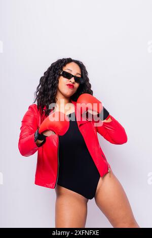 Afrikanische übergroße Frau mit Boxhandschuhen auf Studiohintergrund, schöne dunkelhäutige weibliche Boxerin Stockfoto