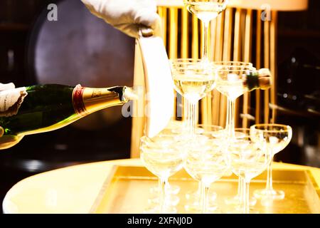 Traditionelles Scheuerritual einer Champagnerflasche durch einen Säbel mit einer Champagnerpyramide, die mit Sektgläsern gebaut wurde, um das blaue Hour-Wochenende zu begrüßen Stockfoto