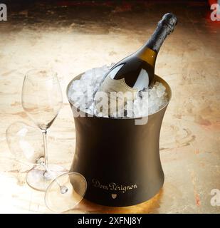 Elegante Flasche Vintage Dom Perignon Champagner in goldgepresstem Eiskühler mit Riedel-Sektglas Stockfoto