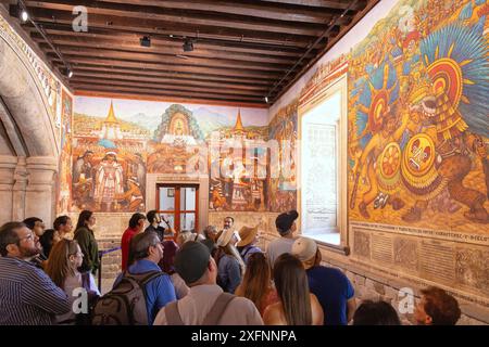 Touristen sehen sich die farbenfrohen historischen Wandmalereien von Desiderio Hernández Xochitiotzin der mexikanischen Geschichte an. Der Regierungspalast, Tlaxcala, Mexiko. Stockfoto