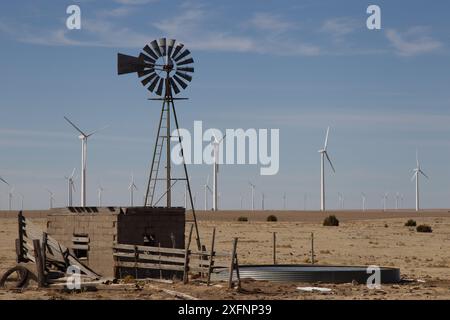 Alt und neu. Wasserpumpe Windmühle im Vordergrund. Windturbinen im Windpark im Hintergrund, südlich von Lamar an der US 287, Colorado. Stockfoto