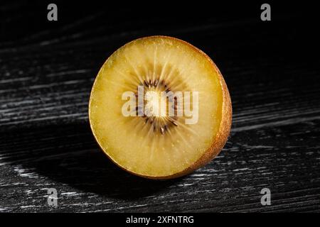 Geschnittene goldene Kiwi auf schwarzem Holzhintergrund Stockfoto