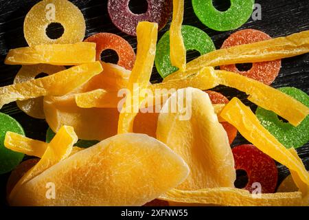 Getrocknete Mango-Cantaloupe-Bonbons auf schwarzem Holzhintergrund von oben Stockfoto