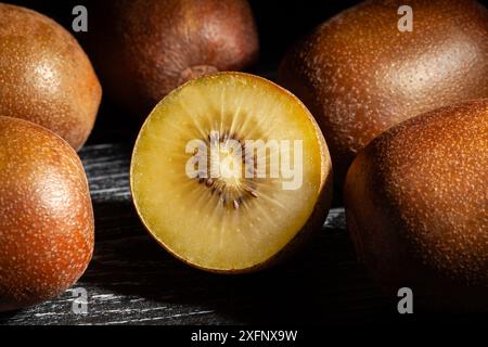 Geschnittene goldene Kiwi auf schwarzem Holzhintergrund Stockfoto