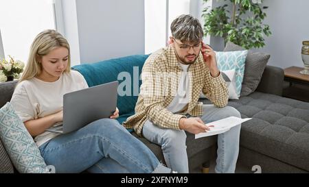 Paare verwalten Haushaltsfinanzen mit Dokumenten und Laptop in ihrem gemütlichen Wohnzimmer Stockfoto