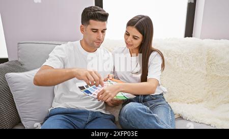 Ein Mann und eine Frau saßen bequem auf einem Sofa und untersuchten gemeinsam Farbmuster in einem gemütlichen Wohnzimmer. Stockfoto